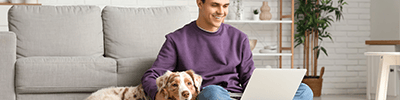 Young-man-with-Australian-Shepherd-dog-using-laptop-at-home-mobile